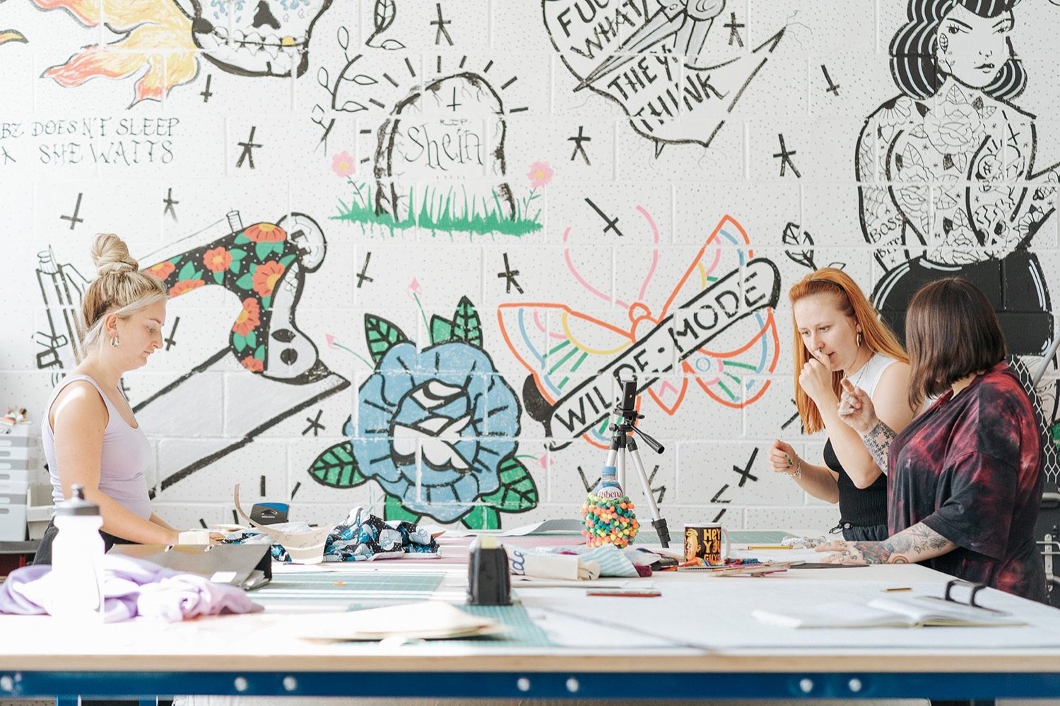 Tenant Wilde Mode in their studio, three people cutting patterns and discussing designs