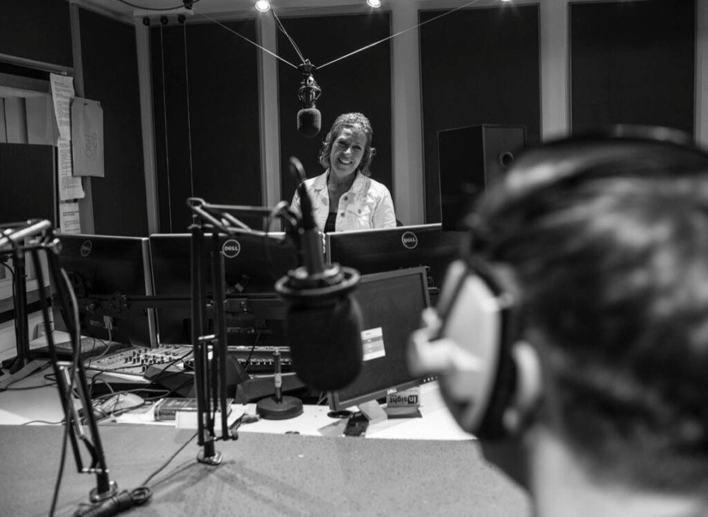 a woman stands next to a mic in a recording studio