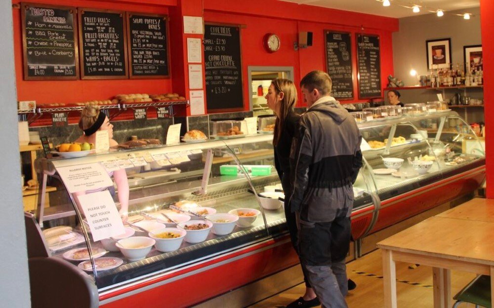 two people stand at counter in a cafe